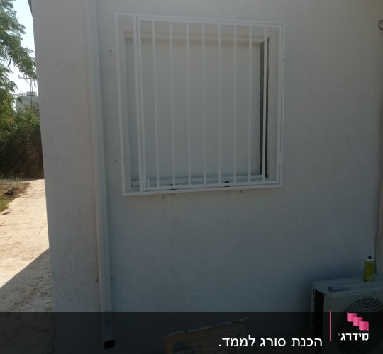 חלון עם סורגים לבנים על קיר חיצוני